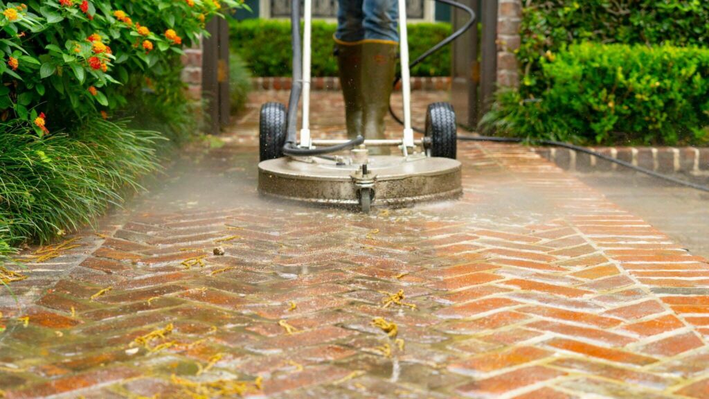 An image of a person power washing brick patio pavers.