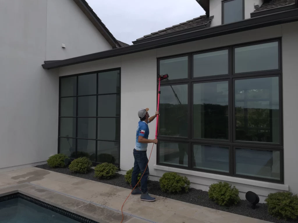 Man cleaning a window glass stain on a big house.