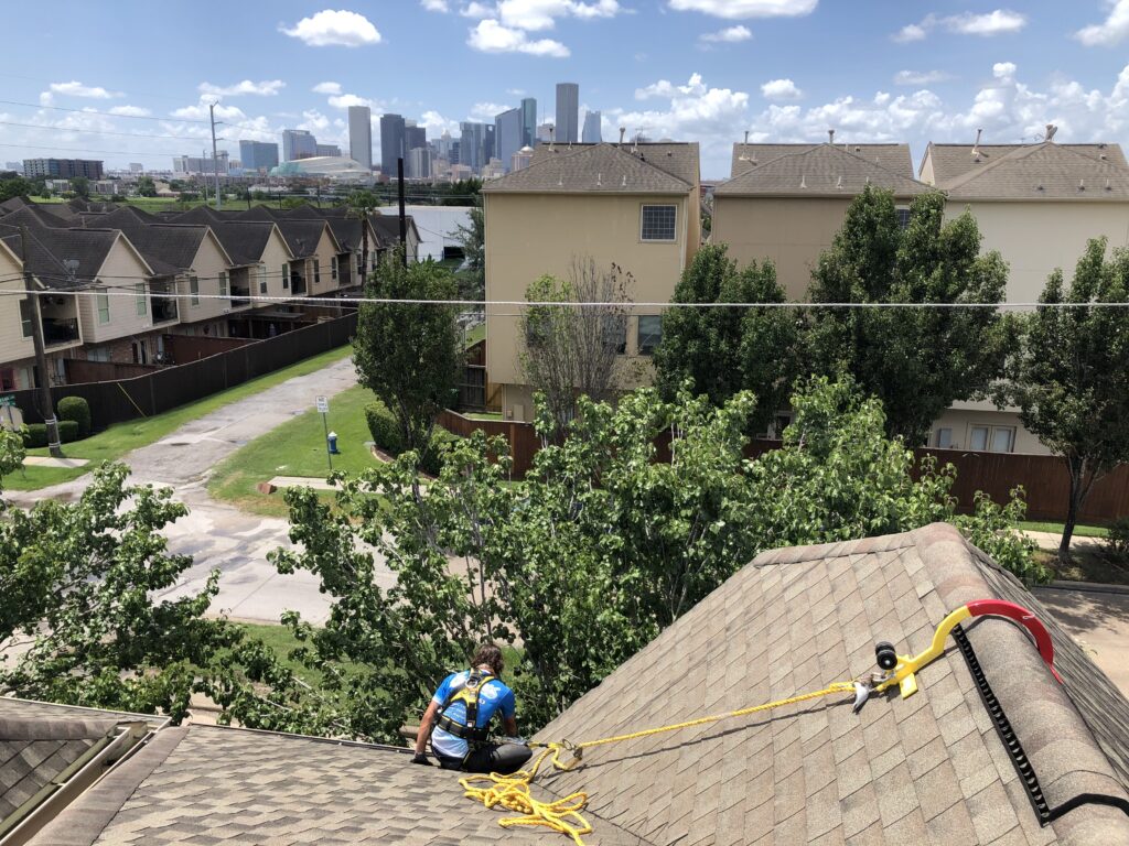 Man harnessed on top of roof providing gutter solutions to house