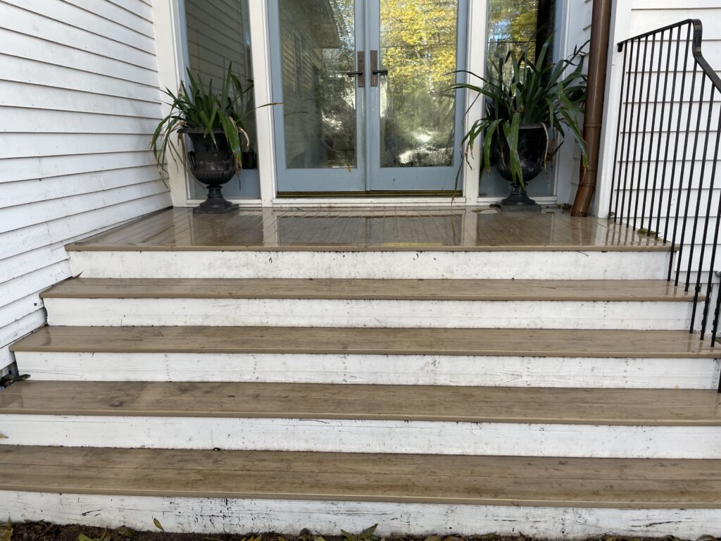 Dirty wooden porch steps and deck with mud stains and water spots showing need for pressure washing deck to remove dirt and restore clean appearance