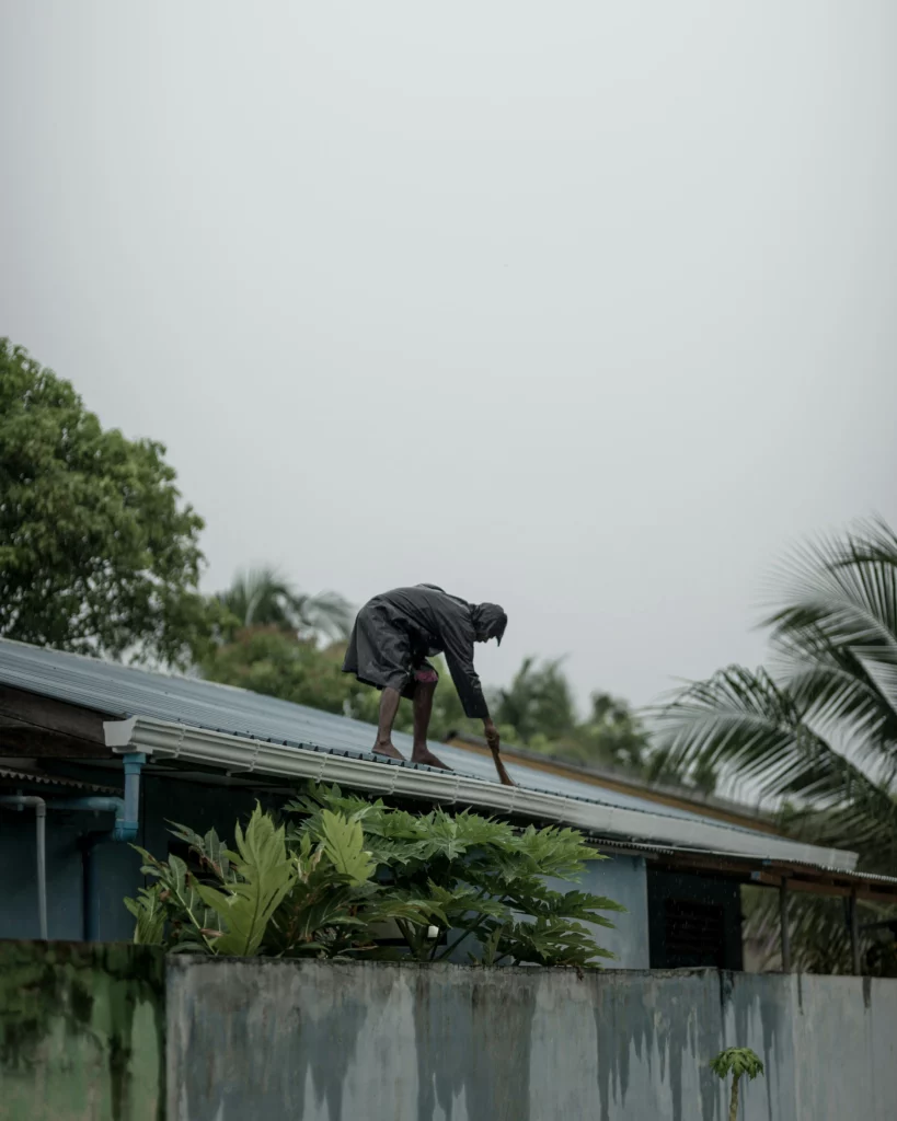 A man standing on a roof checking its' condition.