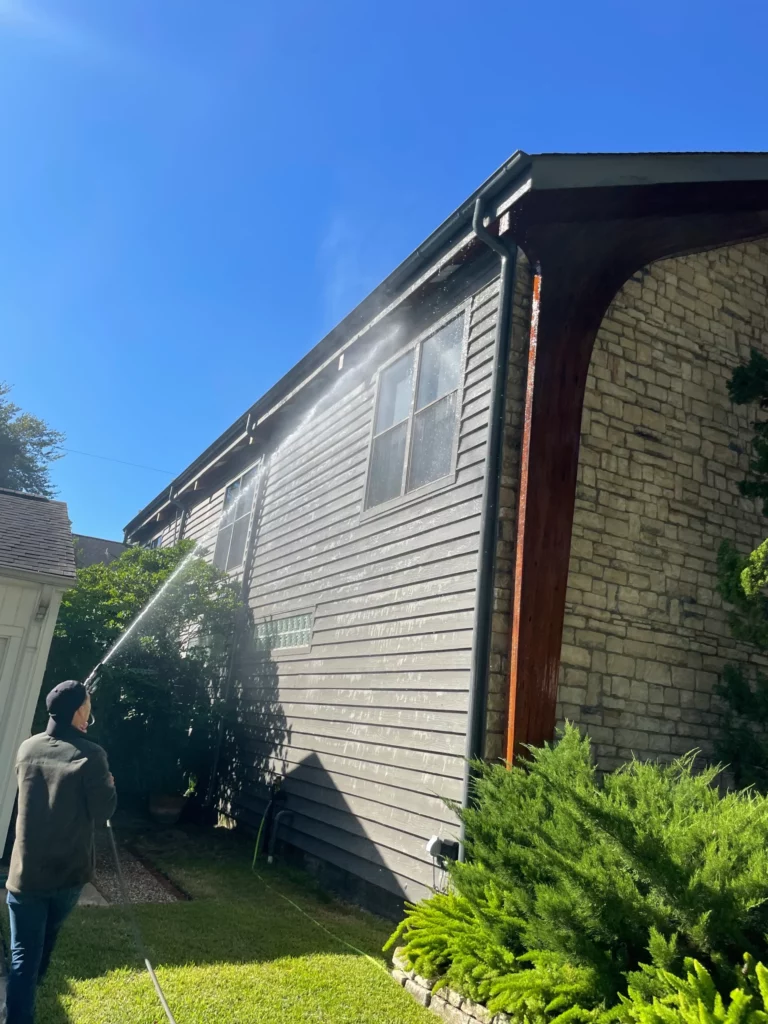 A man pressure washing the sides of a house with siding demonstrating how often you should pressure wash your house,