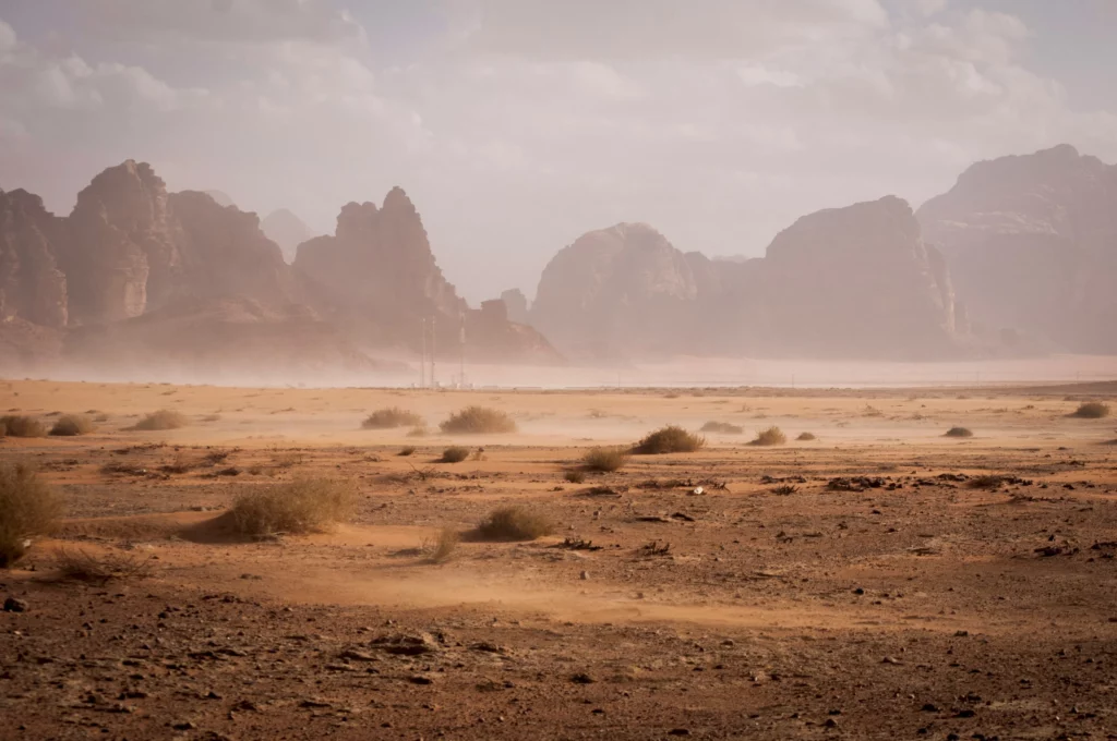 A photo of a dry and dusty dessert with mountains in the background.