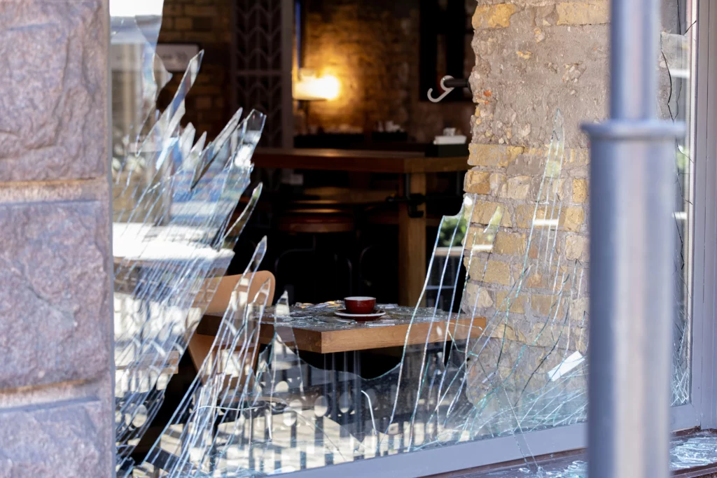 A broken glass window and window screen frame.