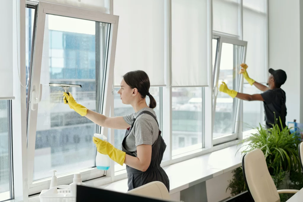 A man and woman Window Cleaning with a Squeegee in an office building.