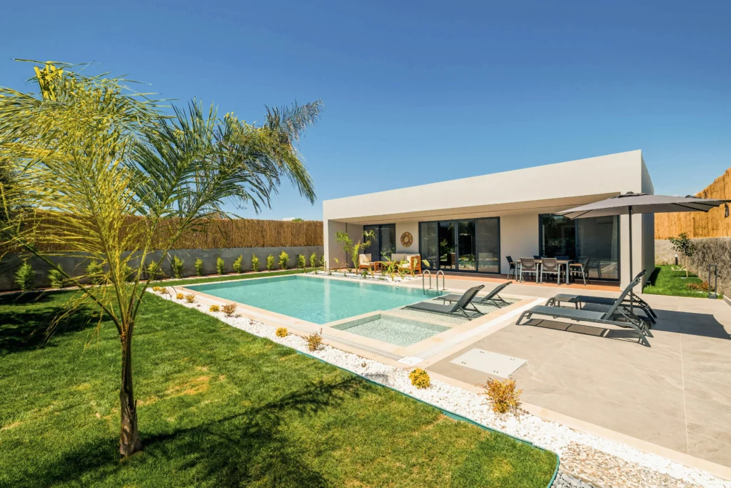 A modern, single story house with a pool near clean patio pavers.