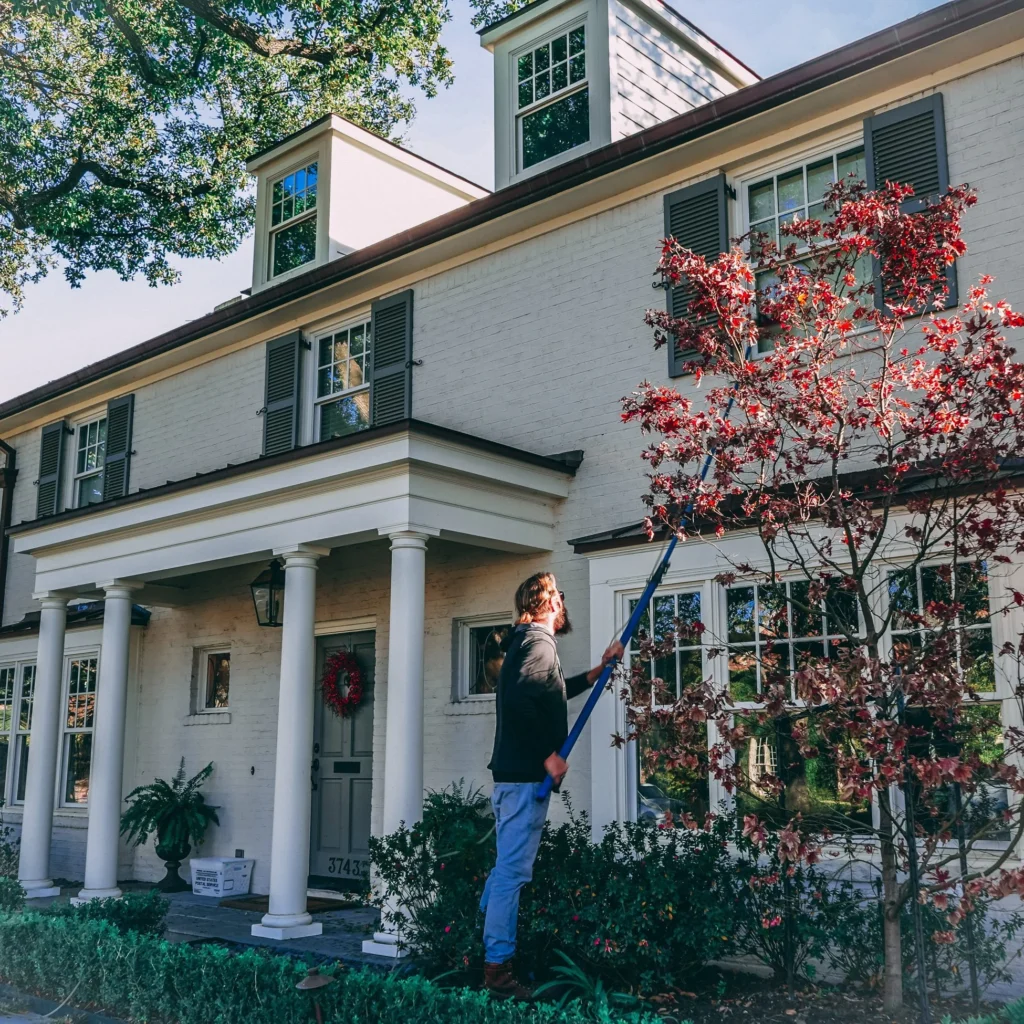 House Facade Styles - a man cleaning the outside of a white brick house.