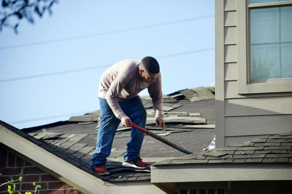 most expensive home repairs - a man standing on a roof repairing it.