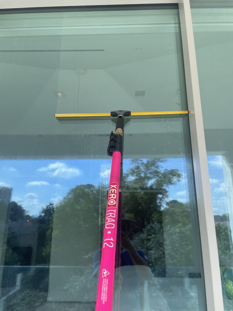 Window Cleaning Tools - Long Pink Squeegee Pole Being Used on Exterior of Glass Door